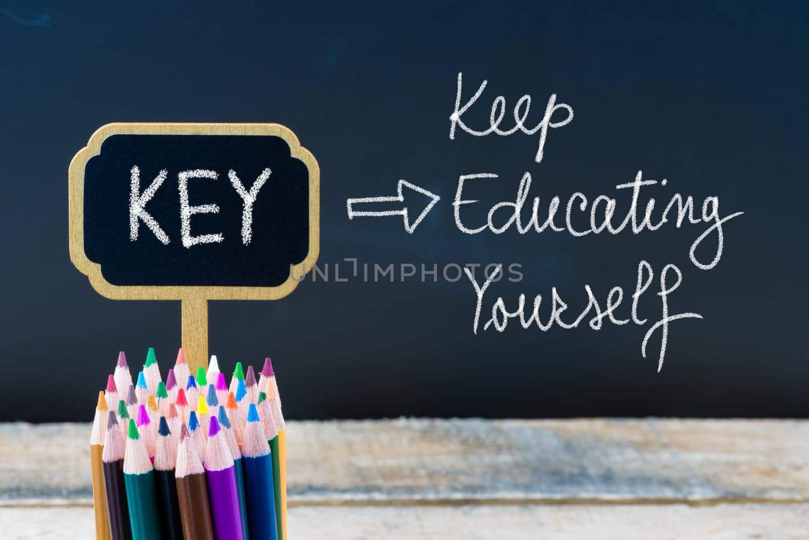 Business Acronym KEY Keep Educating Yourself written with chalk on wooden mini blackboard labels and chalkboard background.