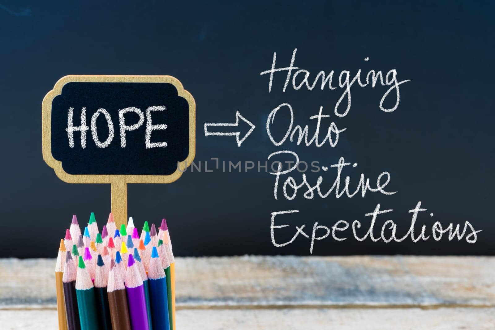 Business Acronym HOPE Hanging Onto Positive Expectations written with chalk on wooden mini blackboard labels and chalkboard background.