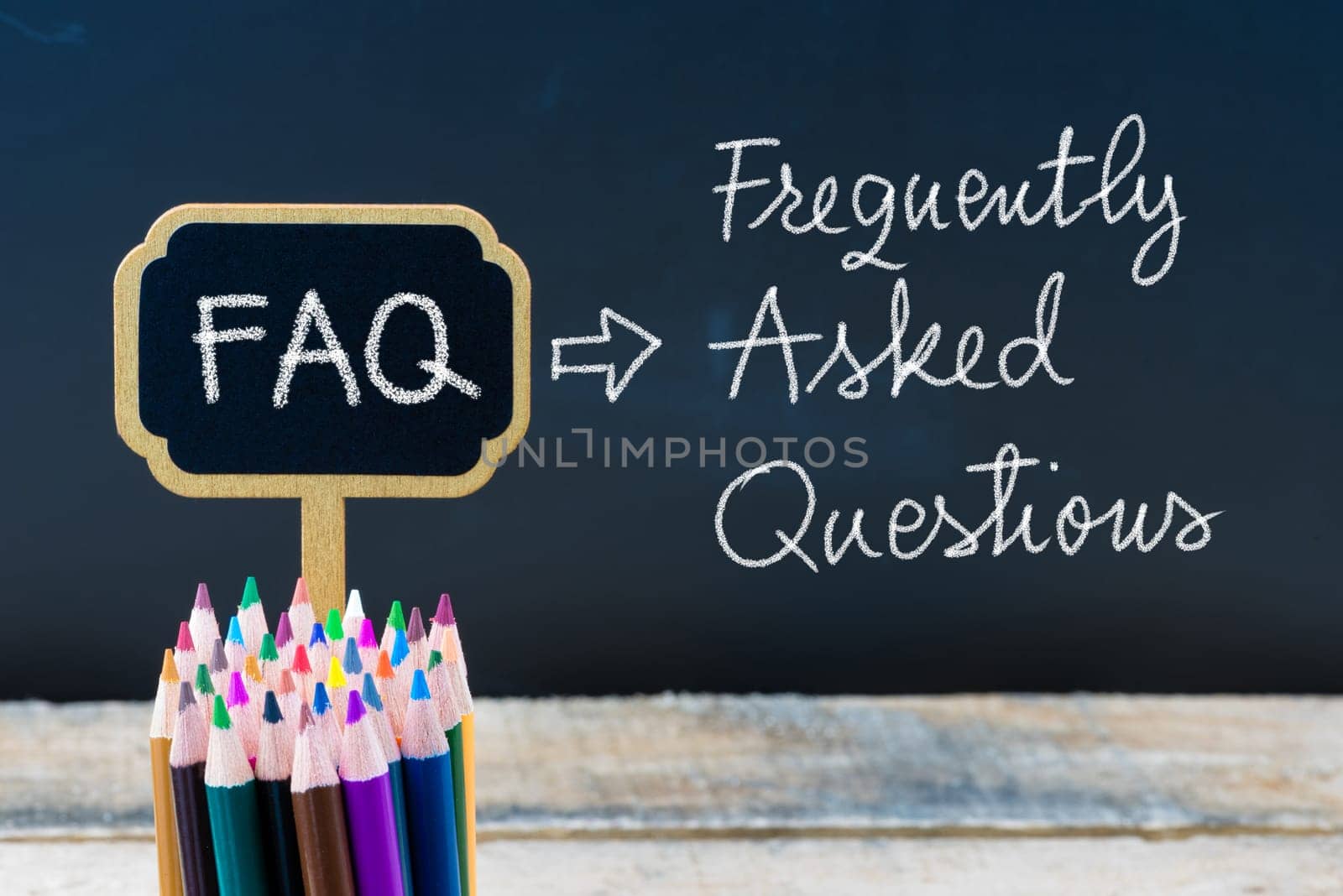 Business Acronym FAQ Frequently Asked Questions written with chalk on wooden mini blackboard labels and chalkboard background.
