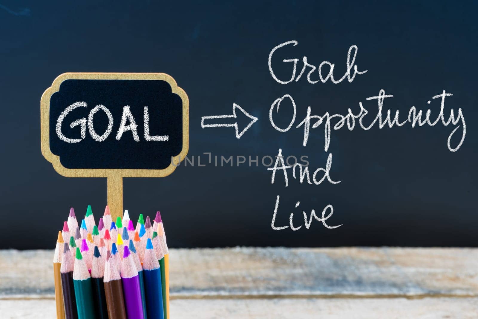 Business Acronym GOAL Grab Opportunity and Live written with chalk on wooden mini blackboard labels and chalkboard background.