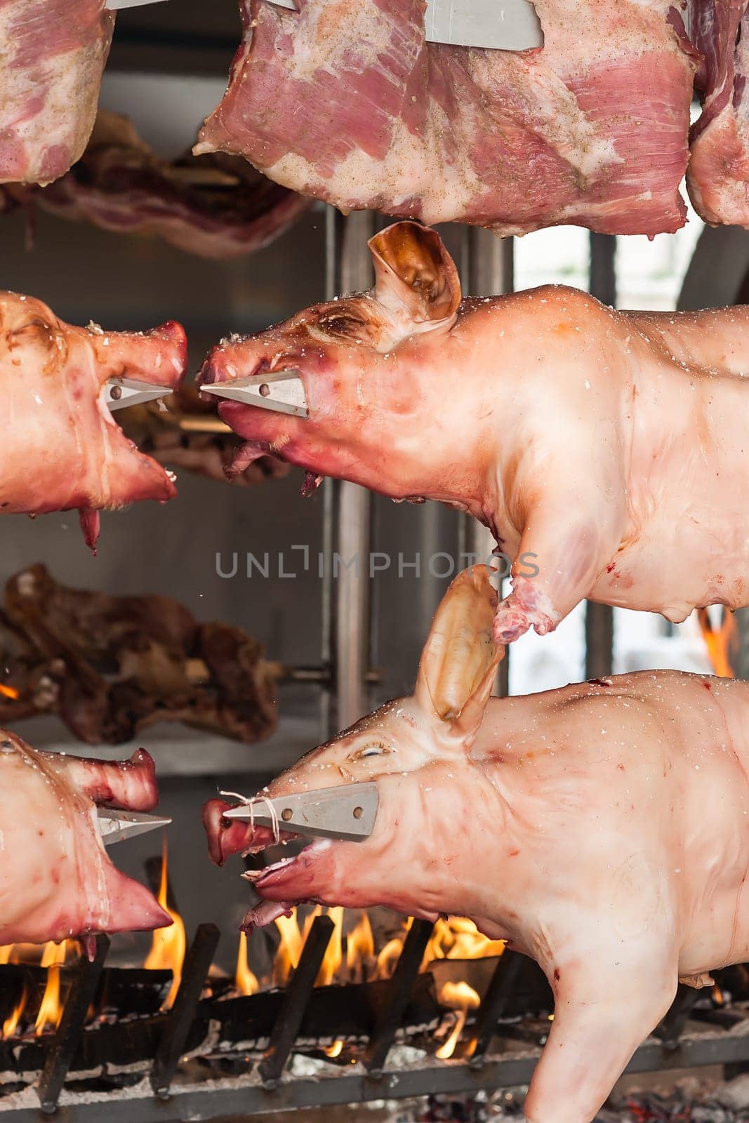 Carcasses of pork and other meat prepared on skewer. Cooking on grill and fire.