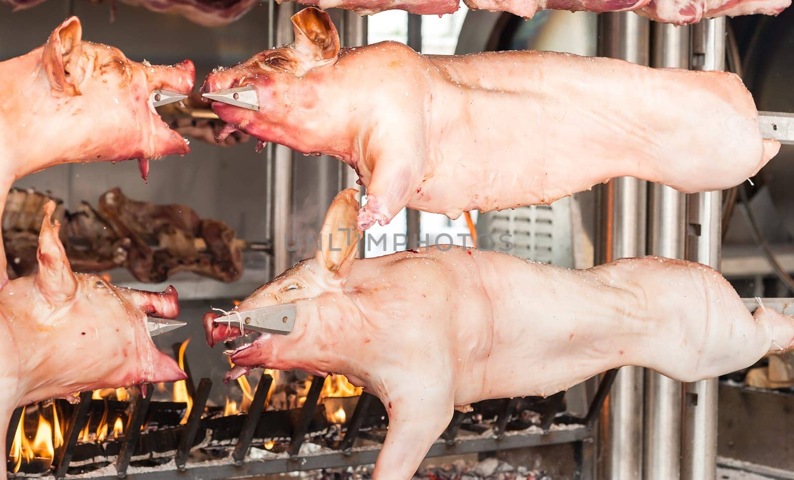 Carcasses of pork and other meat prepared on skewer. Cooking on grill and fire.