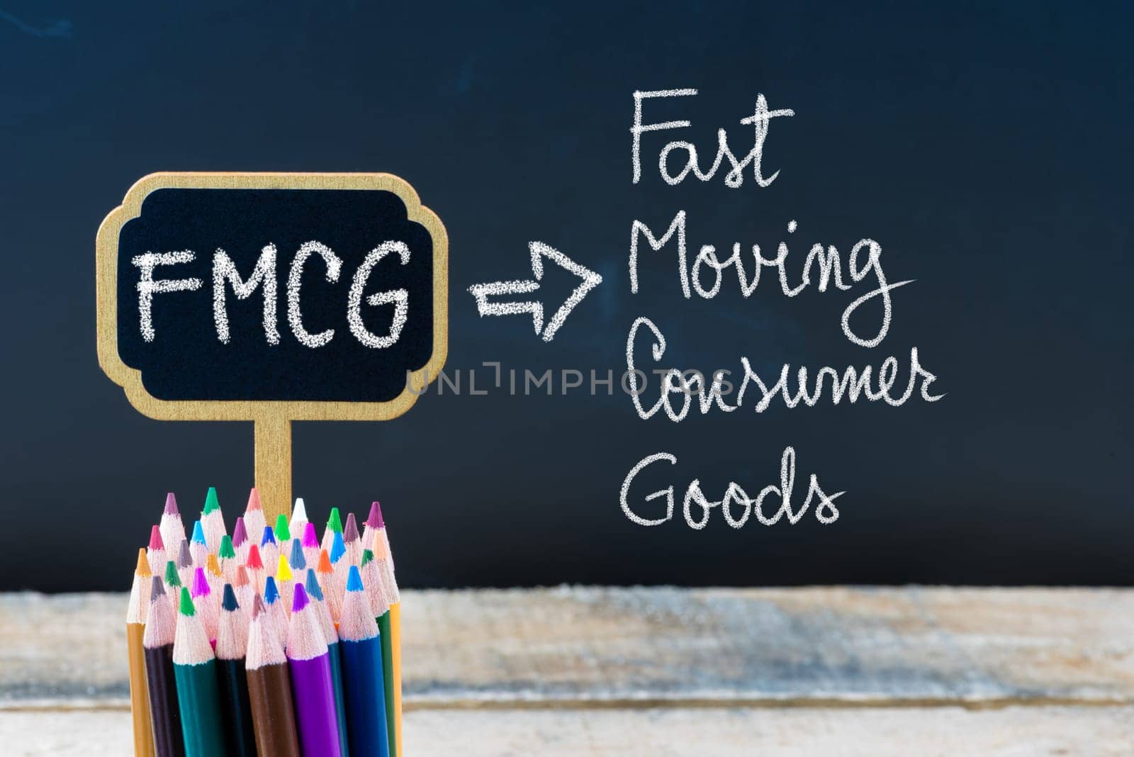 Business Acronym FMCG Fast Moving Consumer Goods written with chalk on wooden mini blackboard labels and chalkboard background.