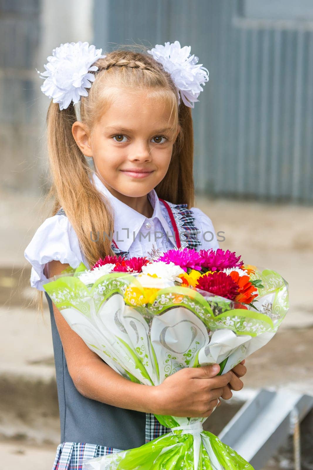 Up portrait of a seven-year school girl with a bouquet of flowers