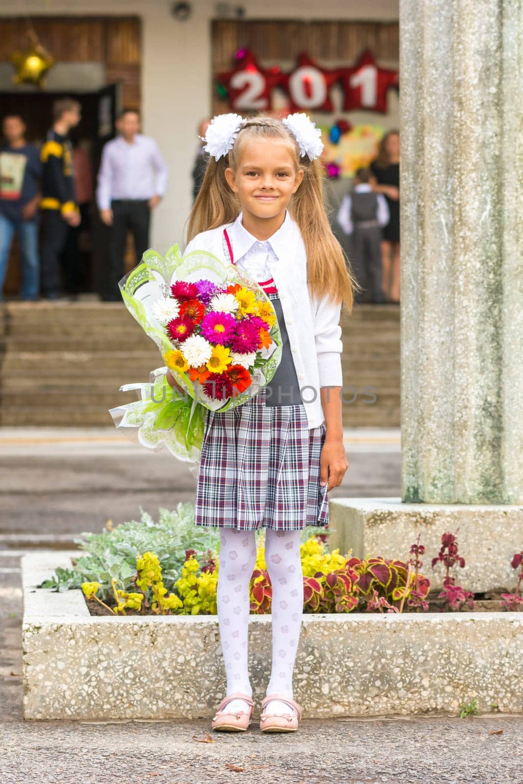 Grower Baby girl first-grader with a bouquet of flowers at the school
