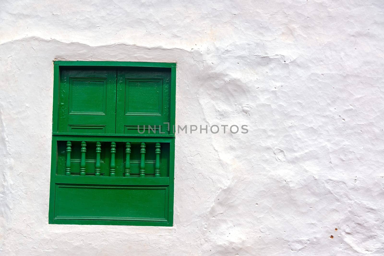 Green window on an old white colonial wall in Barichara, Colombia