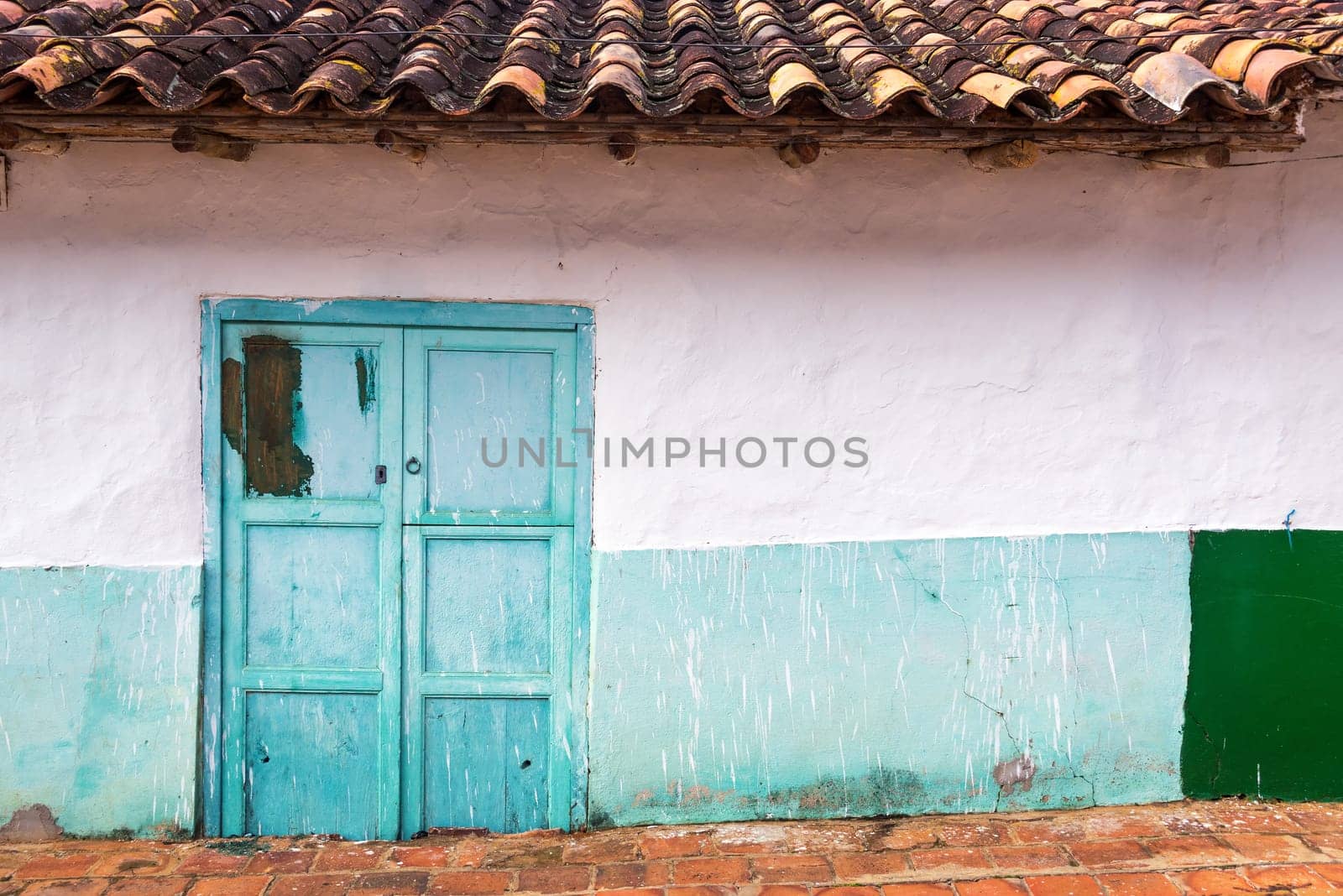 White colonial architecture with a teal door in Barichara, Colombia