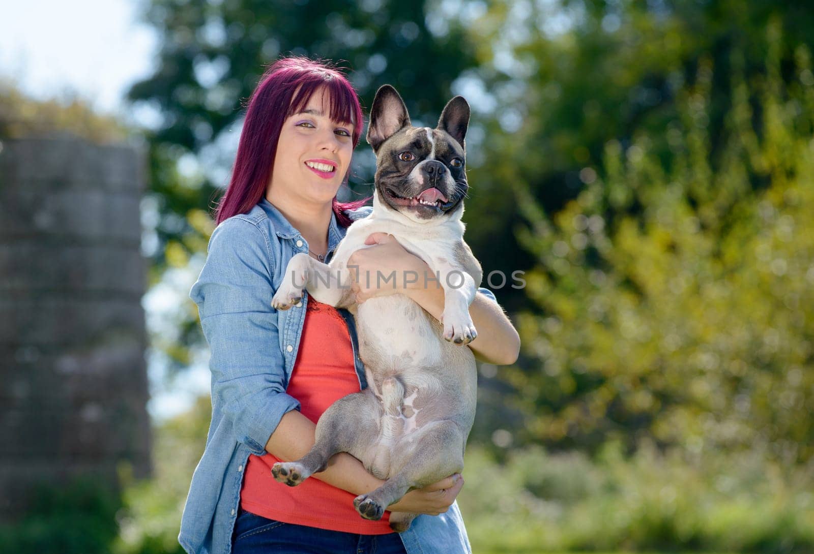 beautiful young woman with her dog french bulldog in the park