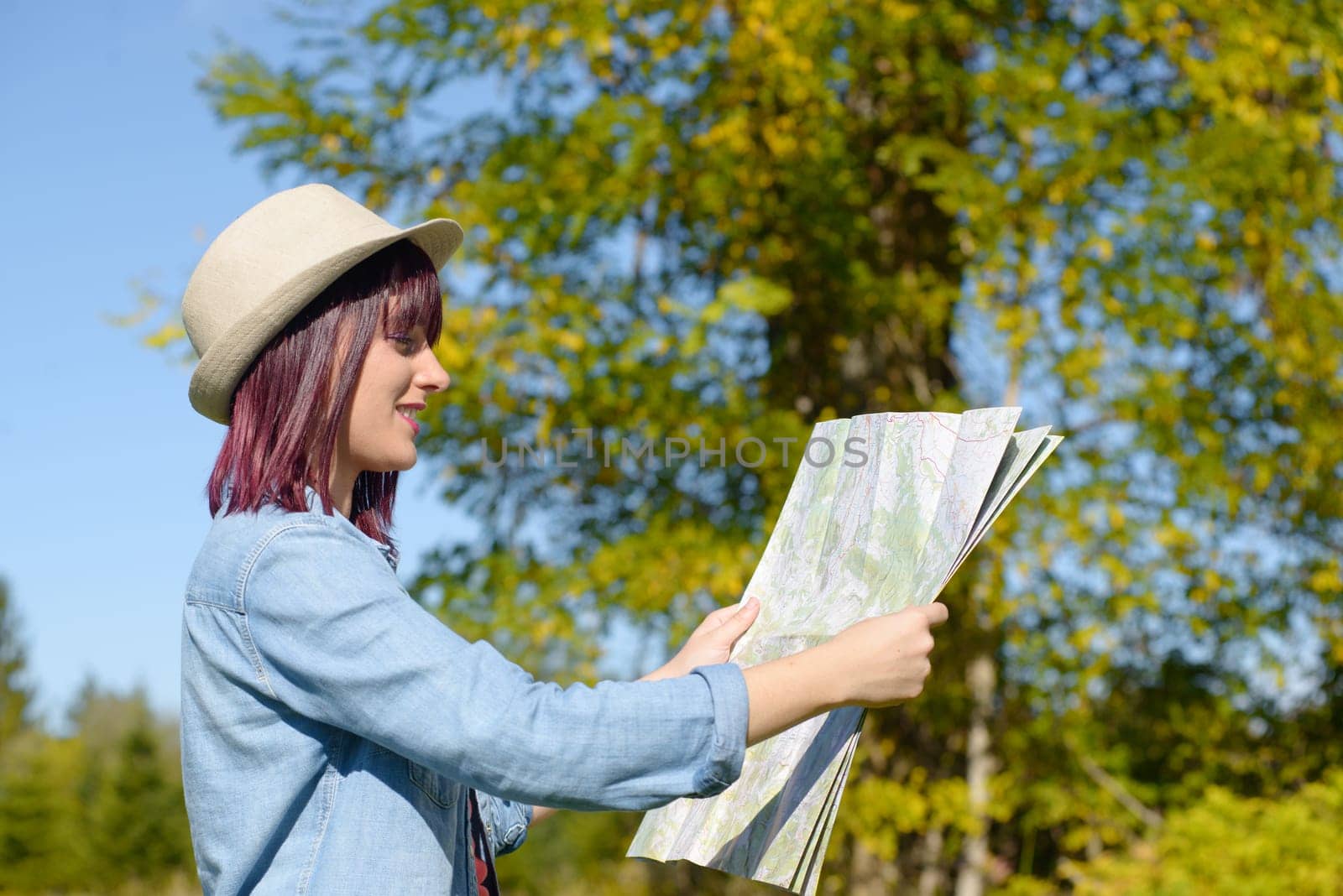 beautiful young woman with hat and map in the countryside