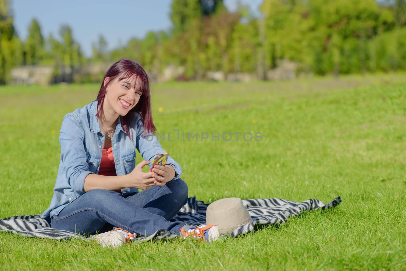 beautiful young woman with red hairs sitting in the grass in the countryside