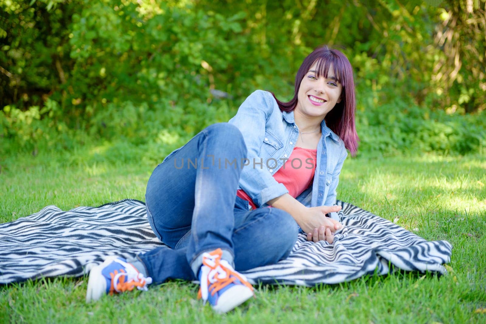 beautiful young woman in jeans lying on the grass, in park