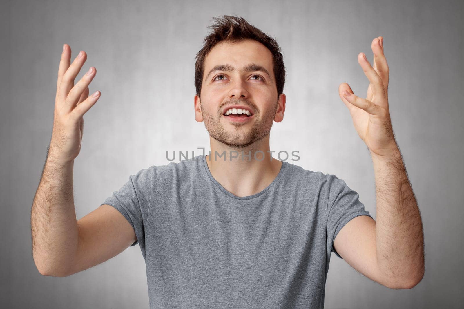Young man looking up and worship God with raised hands