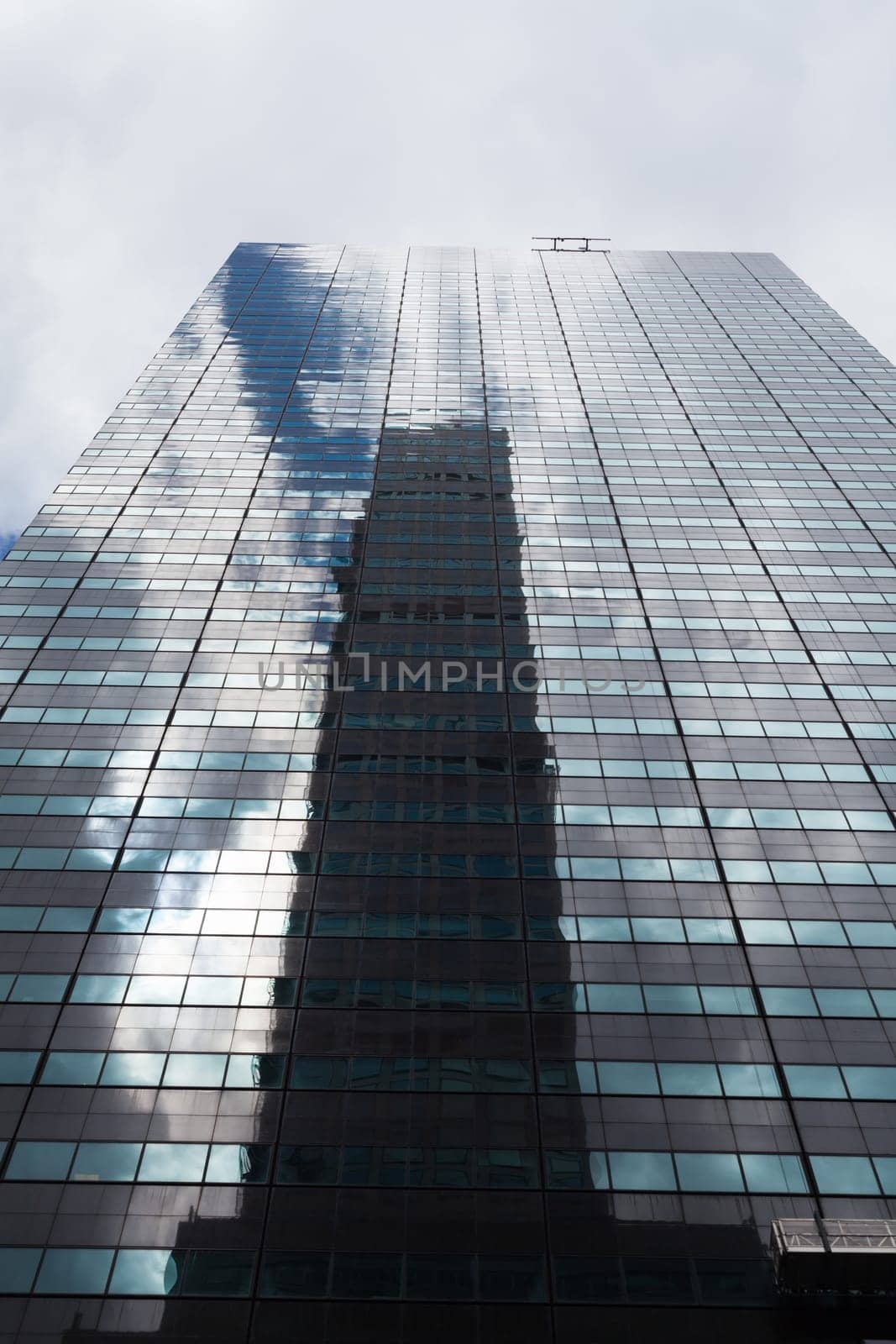 Low angle view of a skyscraper with glass windows and reflections in Manhattan, New York City.