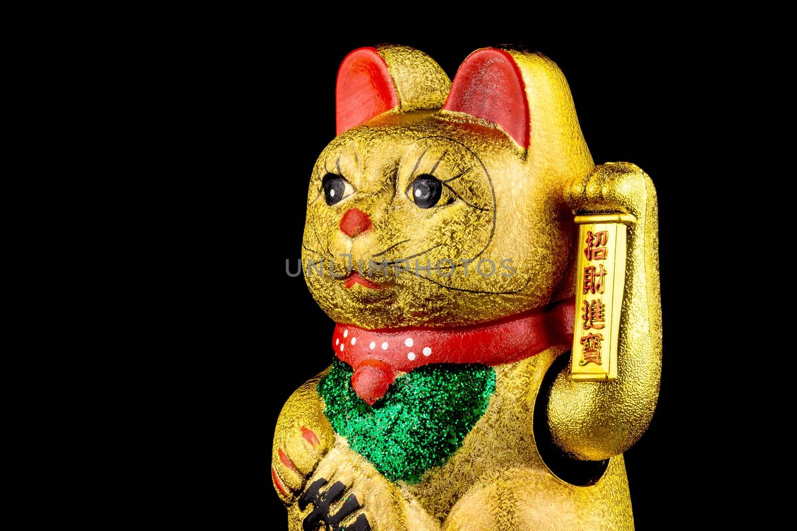 Waving cat,gold-plated welcome cat with waving paw against a black background
