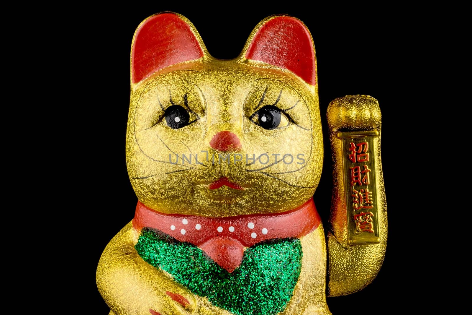 Waving cat,gold-plated welcome cat with waving paw against a black background