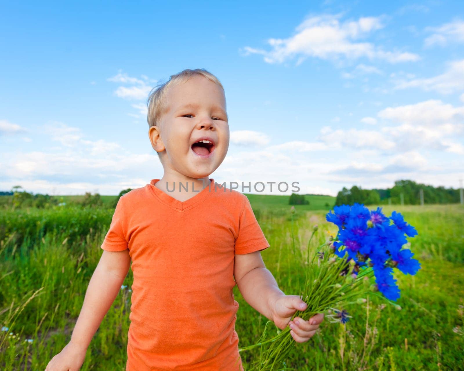 Adorable boy with cornflowers outdoor laughing