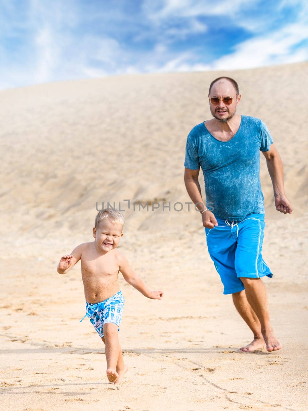 Son and father are running on the beach