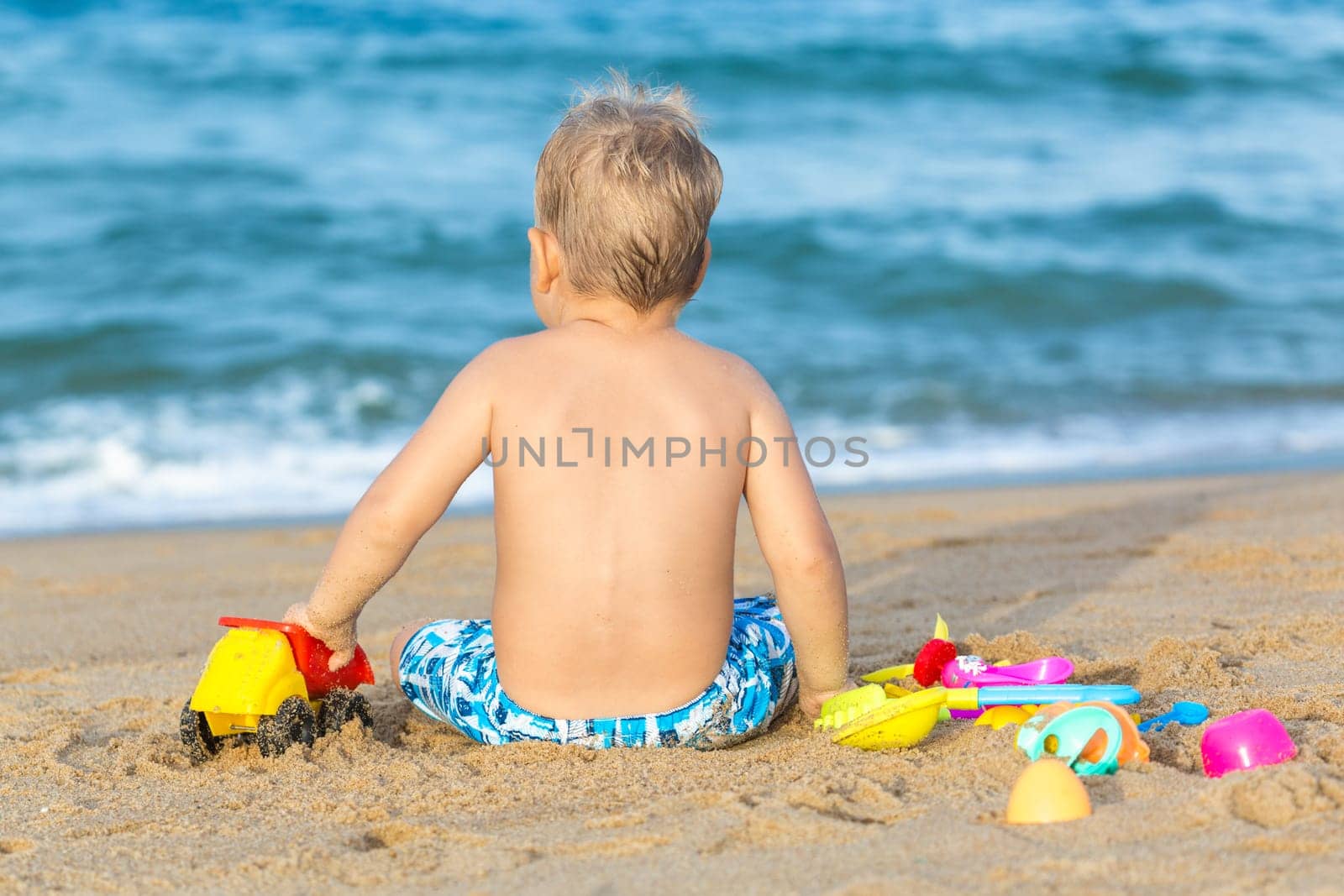 Cute boy on the tropical beach playing toys