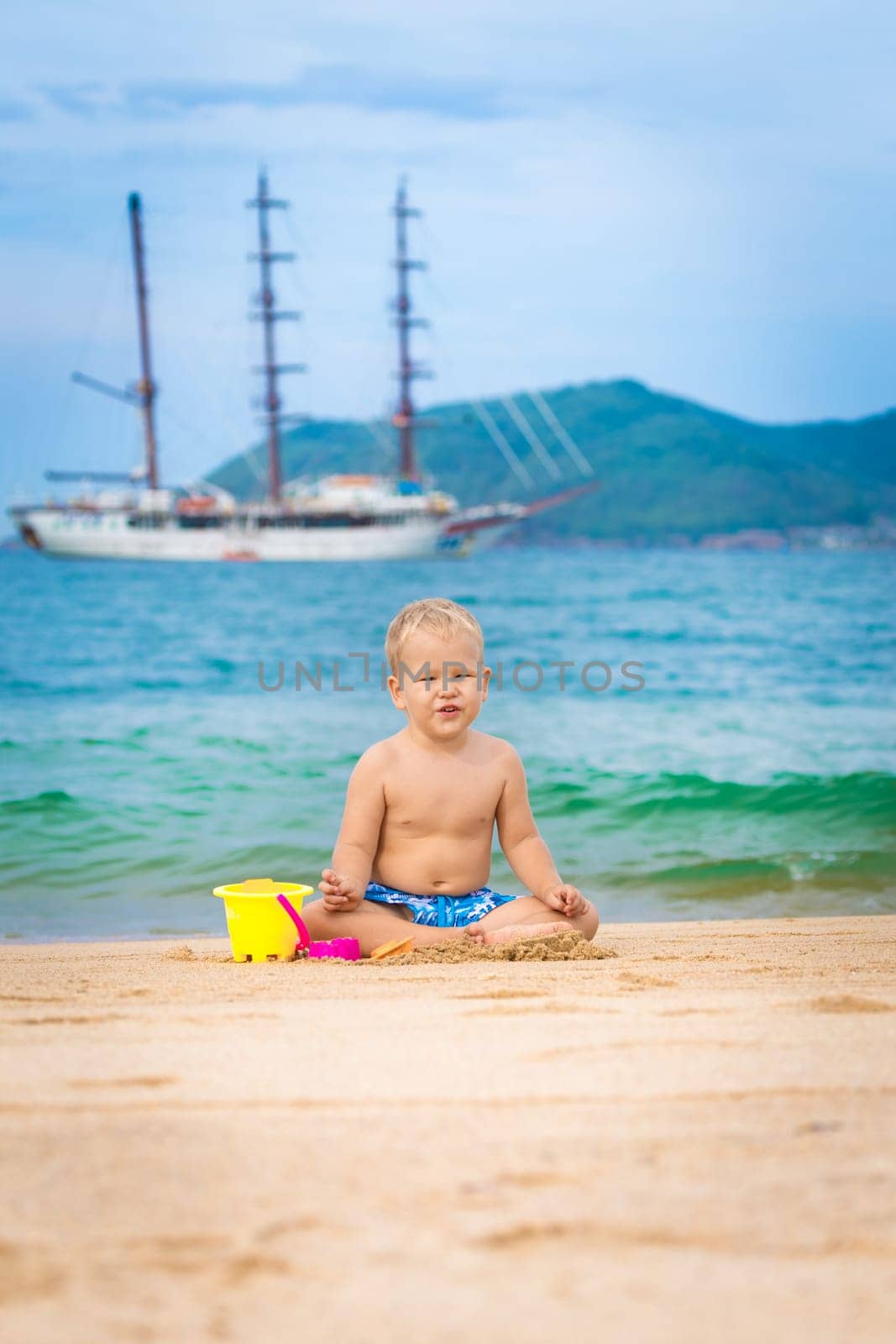 Cute boy on the tropical beach playing toys
