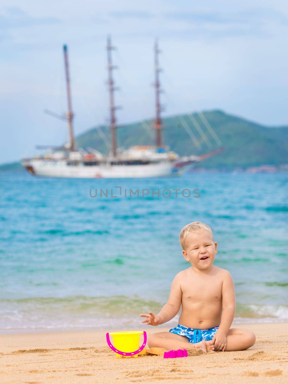 Cute boy on the tropical beach playing toys