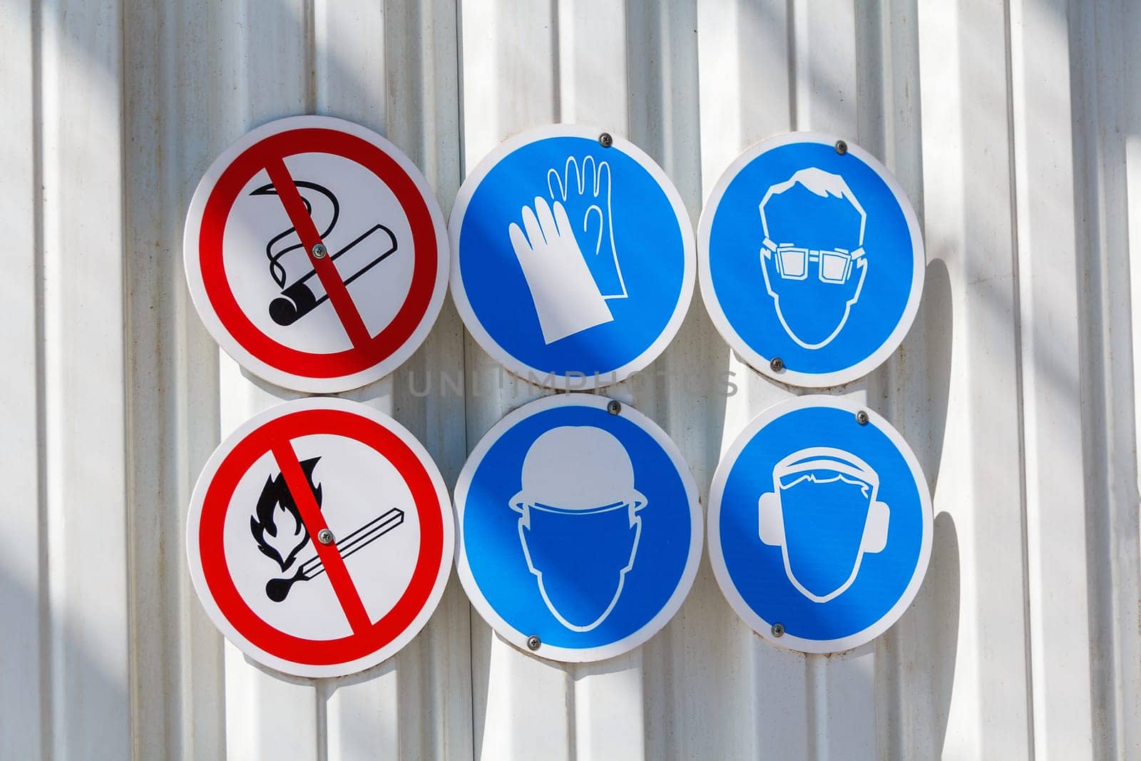 Six warning and caution signs on the metal wall