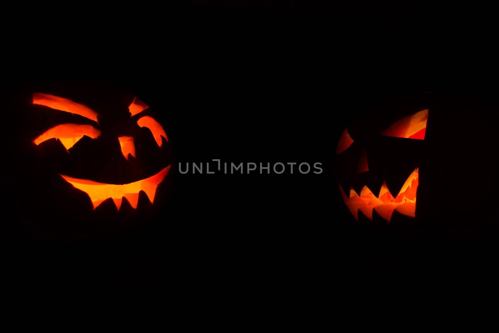 halloween pumpkins with candles inside on black background