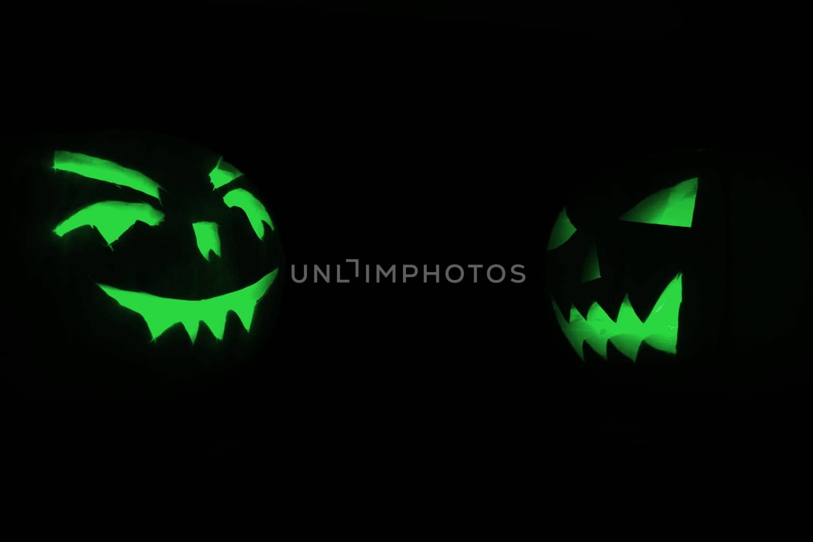 two green halloween pumpkins on black background