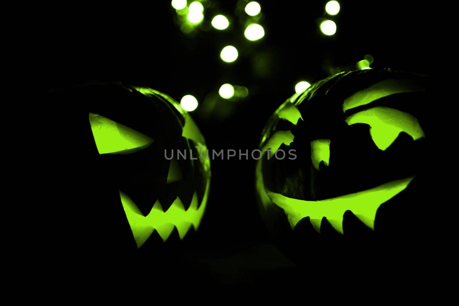 two halloween pumpkins with green bokeh light on black background