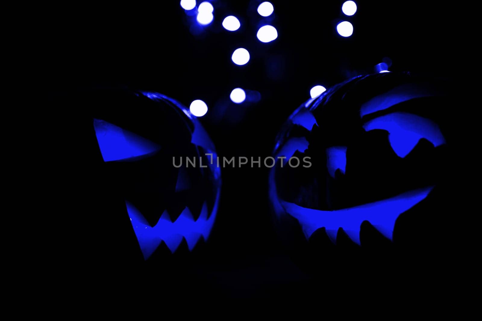 two halloween pumpkins with blue bokeh light on black background