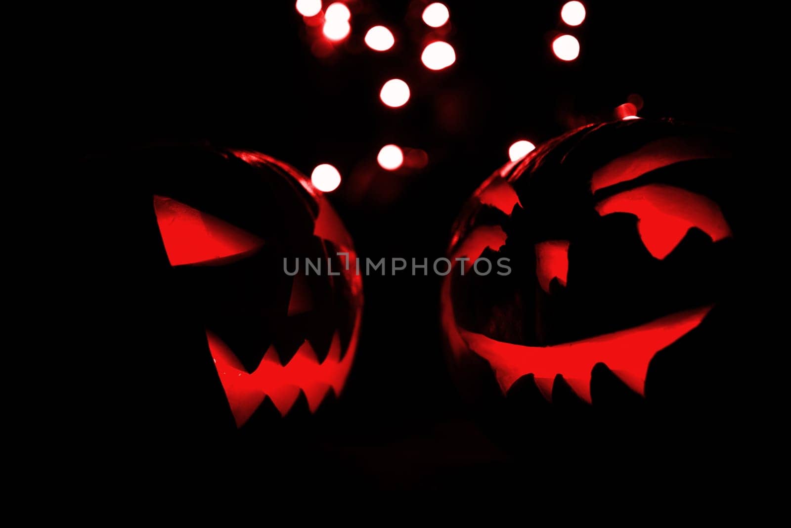 two halloween pumpkins with red bokeh light on black background