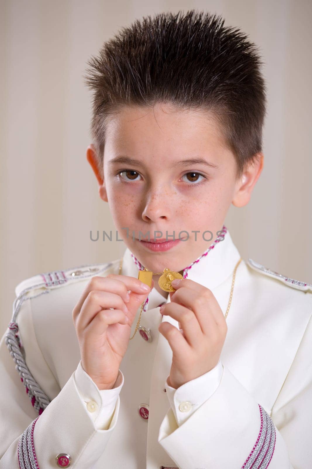 Closeup of a young boy showing his medals and looking at camera in his First Holy Communion