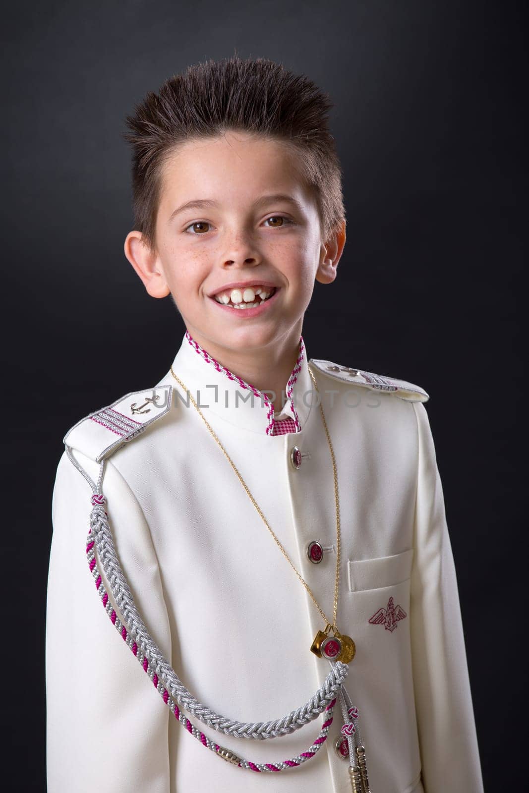 Young boy celebrating his First Holy Communion looking at camera on a black background.