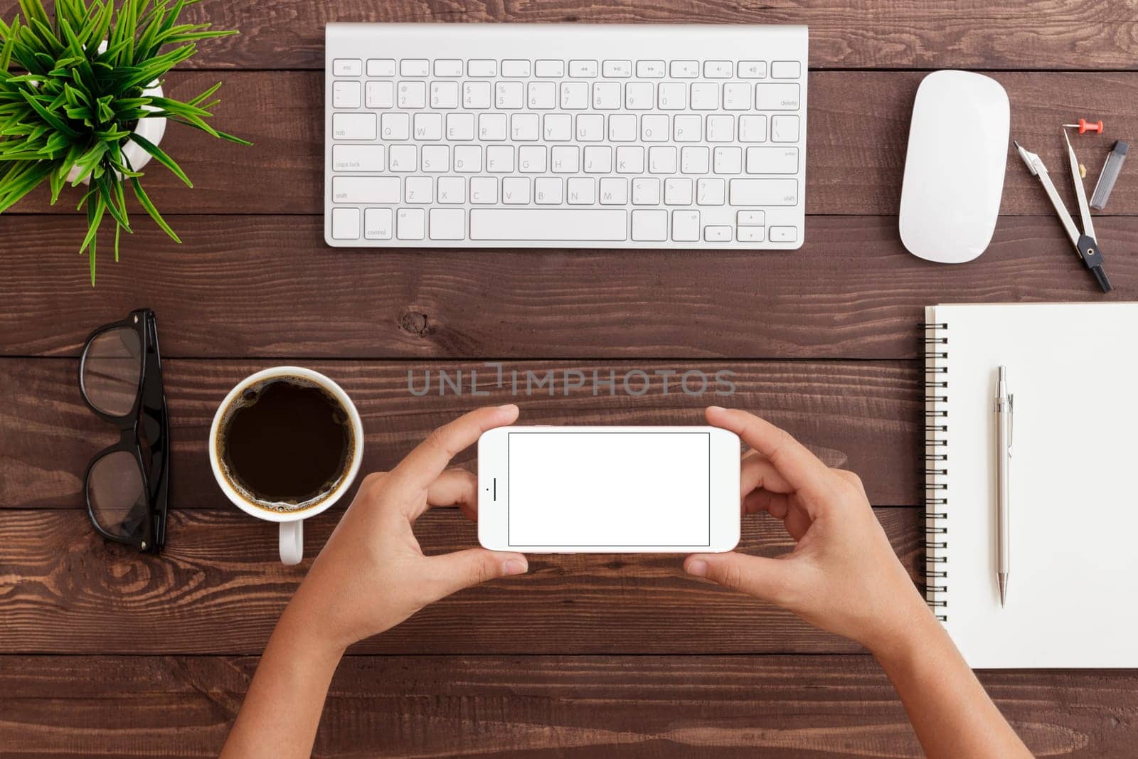 hand holding phone horizontal showing phone blank screen on work table, mock up phone rose gold color