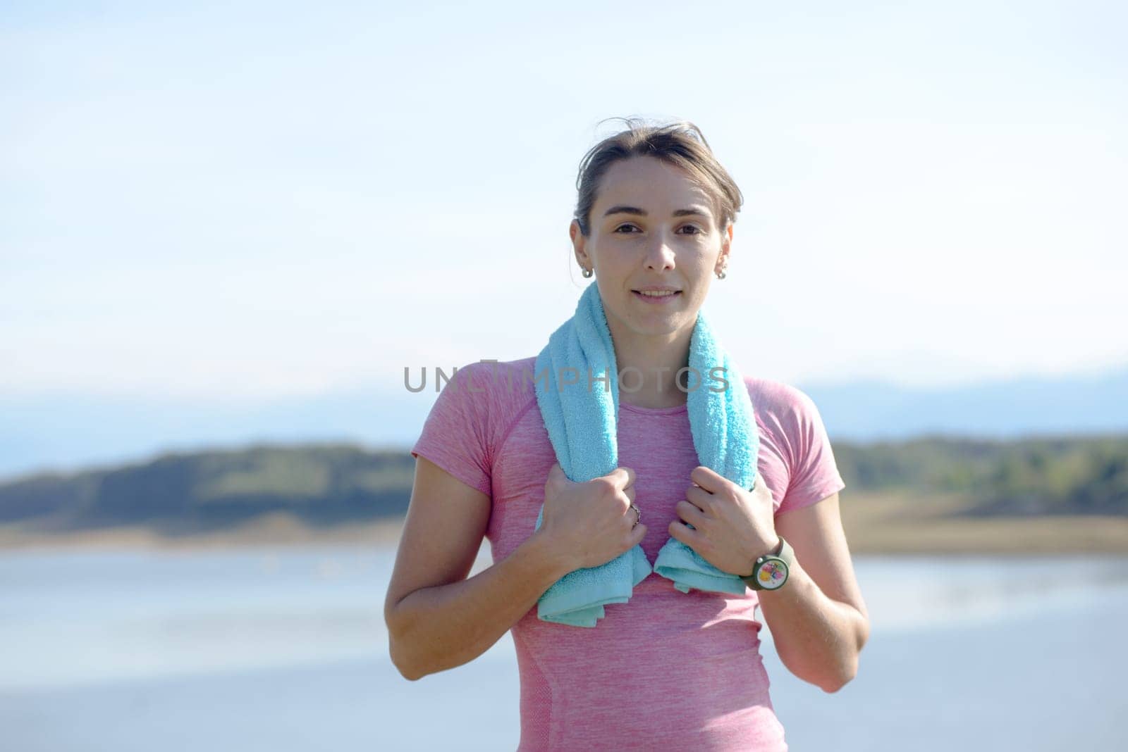 portrait of young sporty woman with blue towel in the countryside