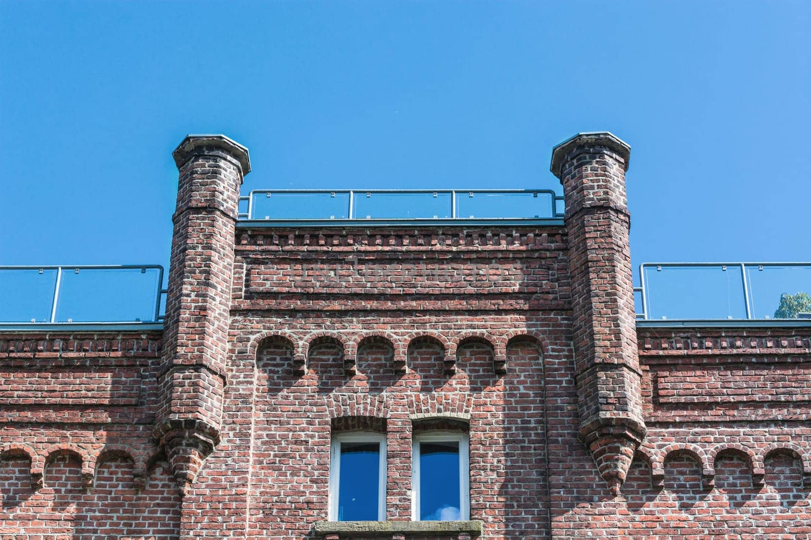 House façade of a typical old brick house in front of a blue sky..