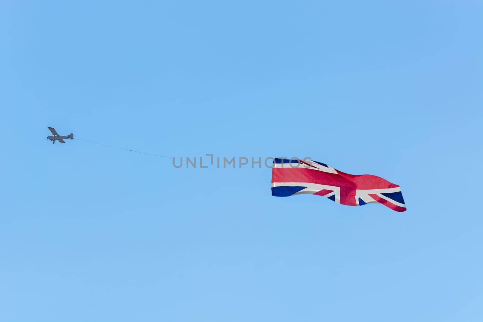 Banner tow,small powered aircraft with tow banner for advertising.. Here is the flag of Great Britain..