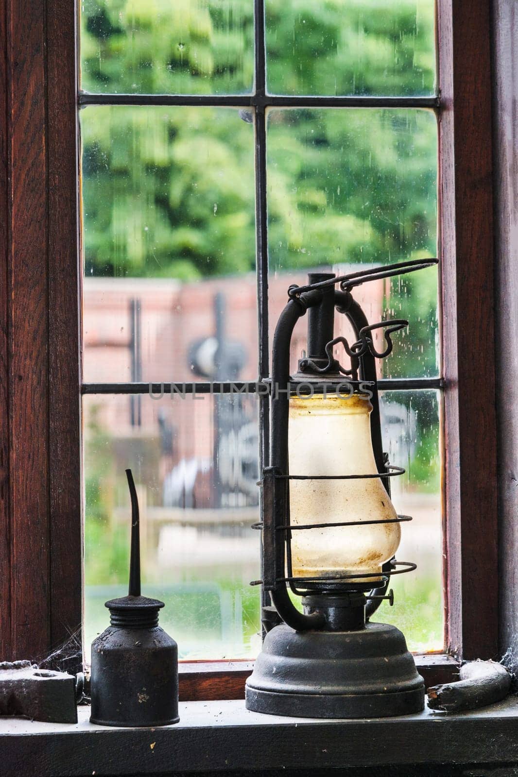 Antique kerosene lamp and oil jug on the windowsill of an old craftsman's workshop..