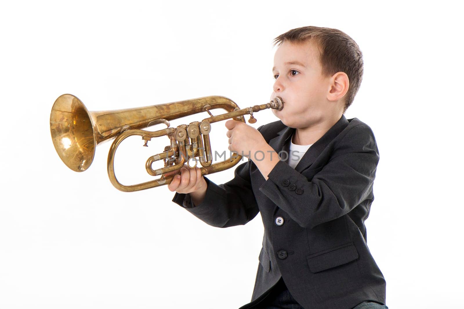 young boy blowing into a trumpet against white background