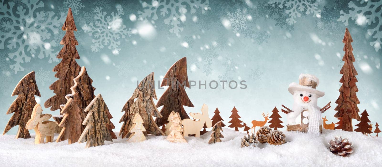 Wooden decoration arranged as a cute winter scene with a snowman,conifer trees,Christmas star,animals and snow,on a snowflakes background