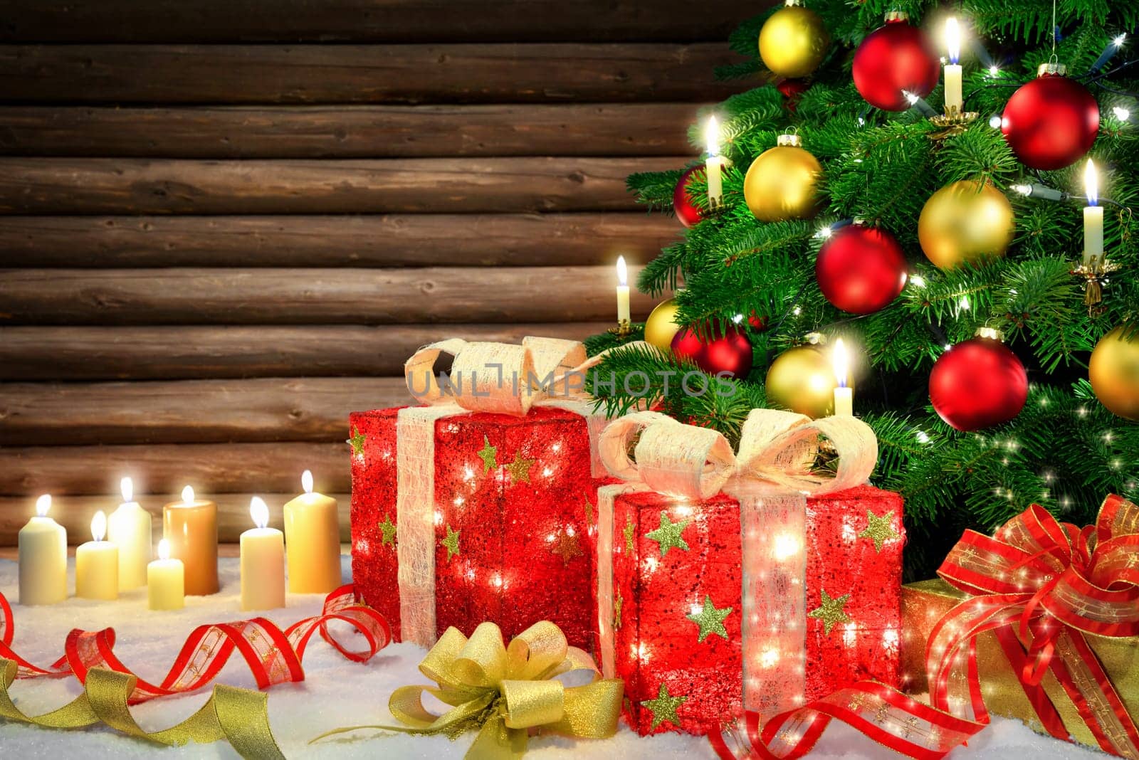 Shiny Christmas scene with a Christmas tree,candles,ornamental gift boxes with lamps,bows,snow and a rustic wooden wall background
