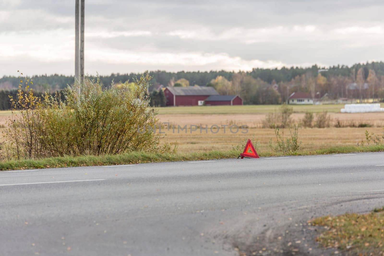 Warning Triangle on Road with field in the background.