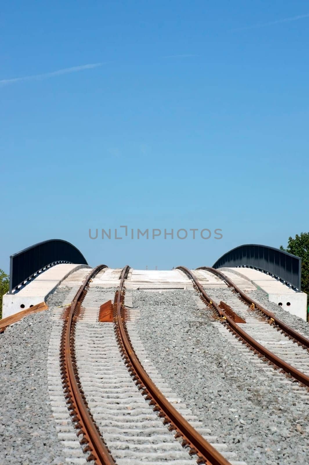 A newly built bridge and rail line for trams with rails,ballast and railings.