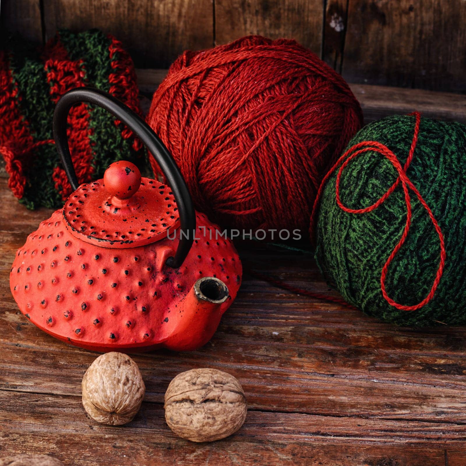 Stylish teapot with warm tea and balls of wool to knit