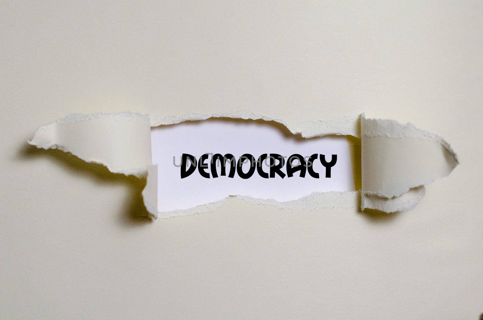 The word democracy appearing behind torn paper