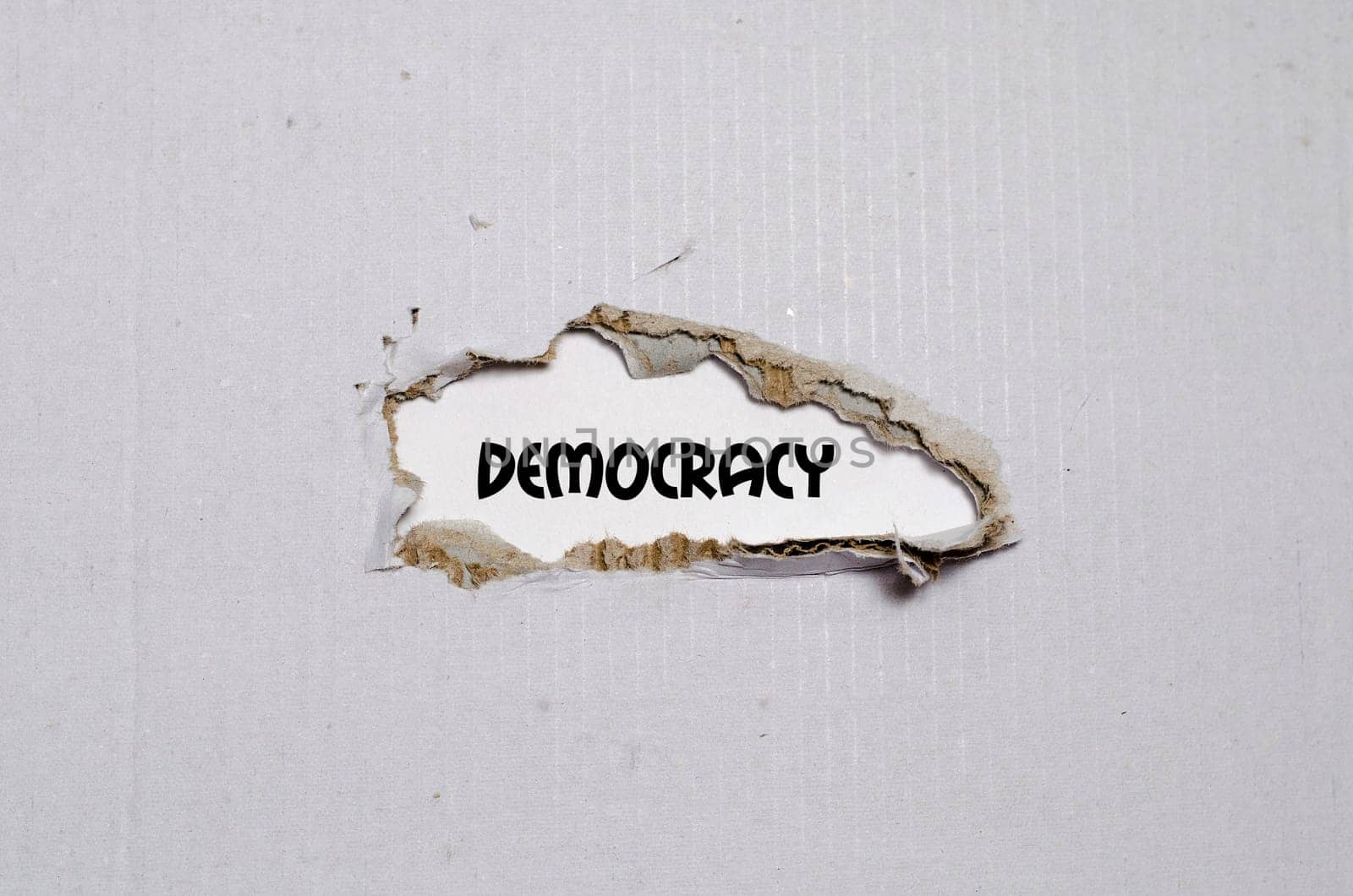 The word democracy appearing behind torn paper