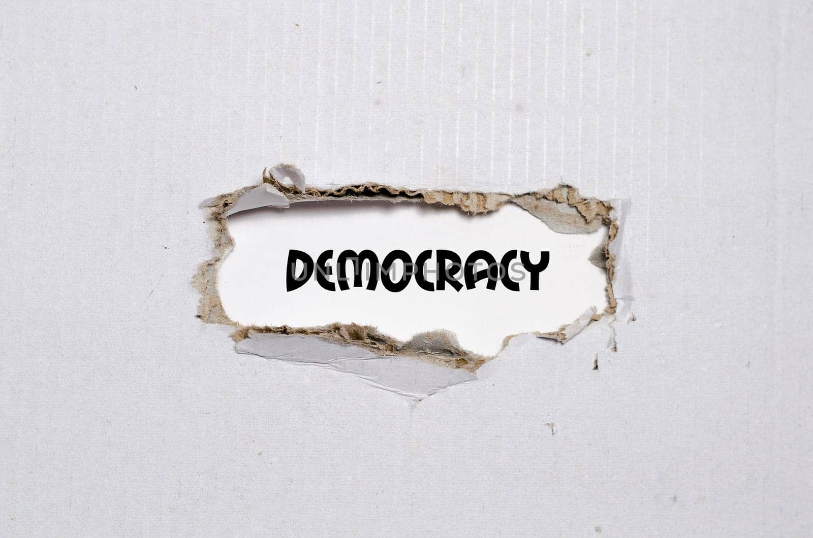 The word democracy appearing behind torn paper