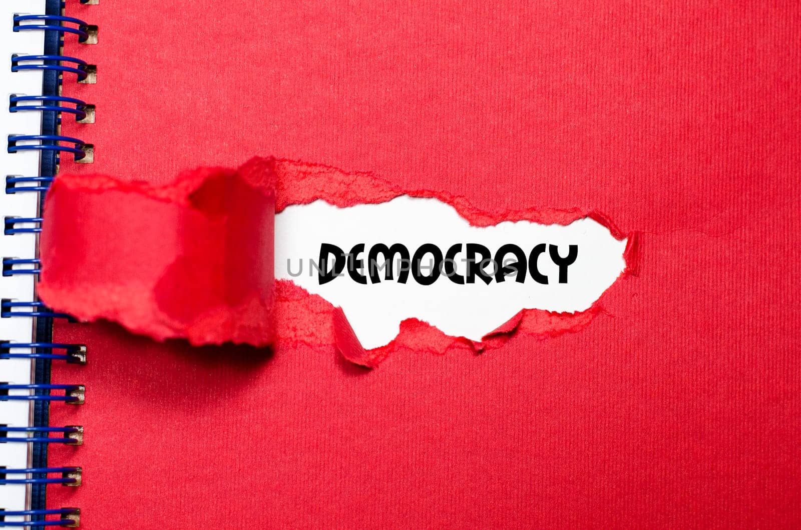 The word democracy appearing behind torn paper