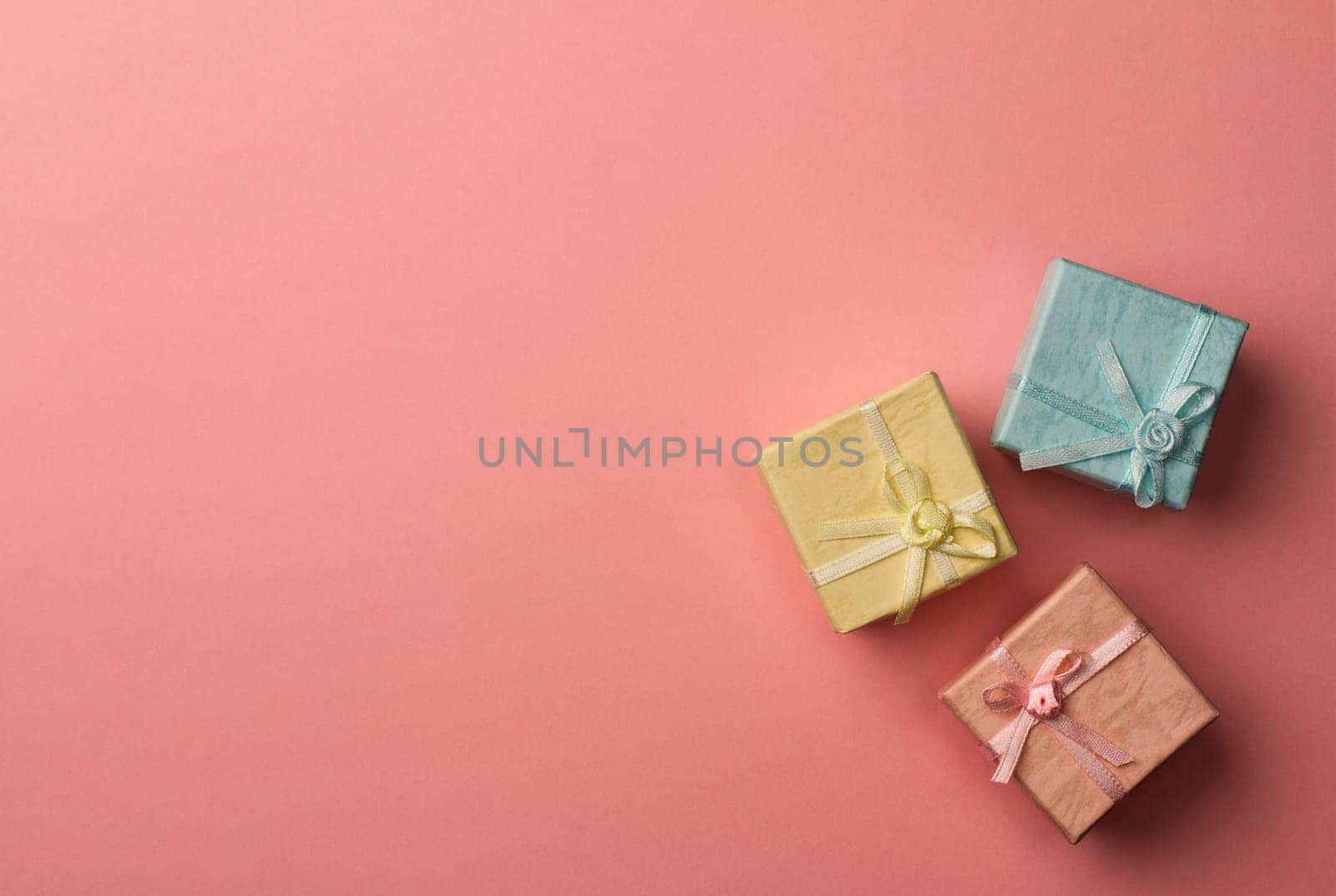 Top view of three small cardboard rectangular gift boxes on red paper background with copy space