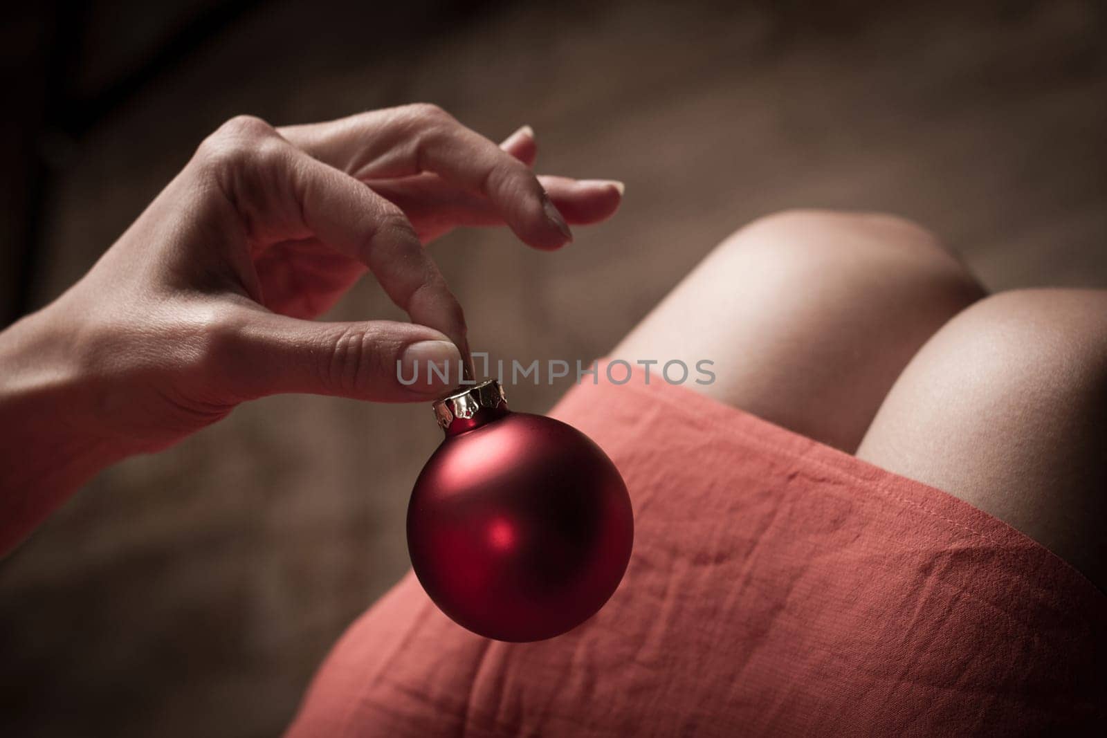 Woman with red dress holding a red Christmas globe with her fingers