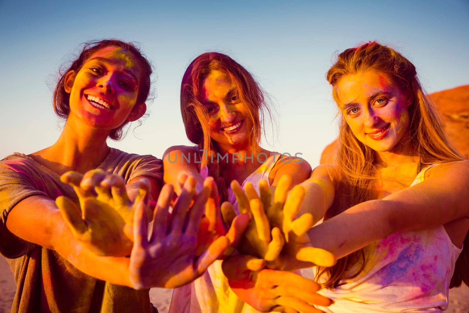 Teenagers playing with colored powder on the beach